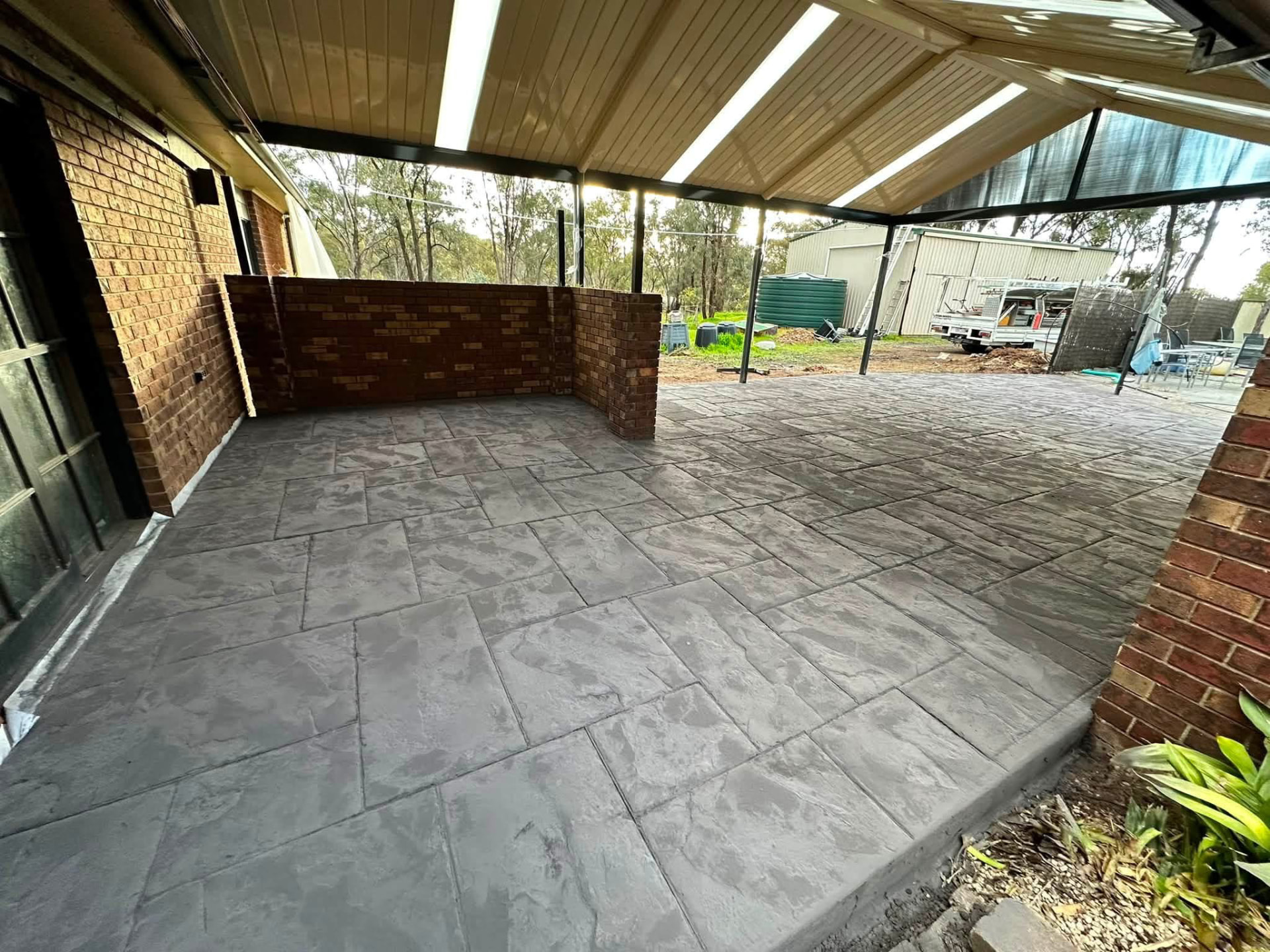 Charcoal slate-pattern stamped concrete alfresco area completed by Tom Body Concrete
