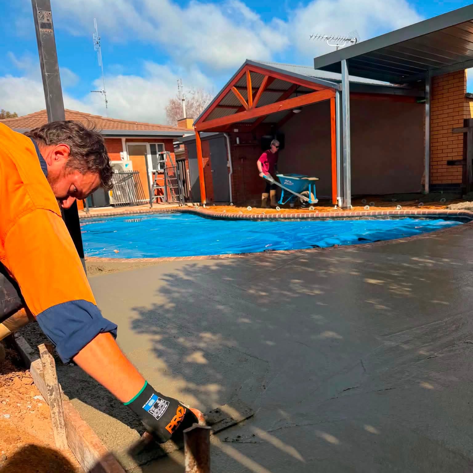 Tom Body Concrete crew hand-finishing a fresh pour around a backyard pool